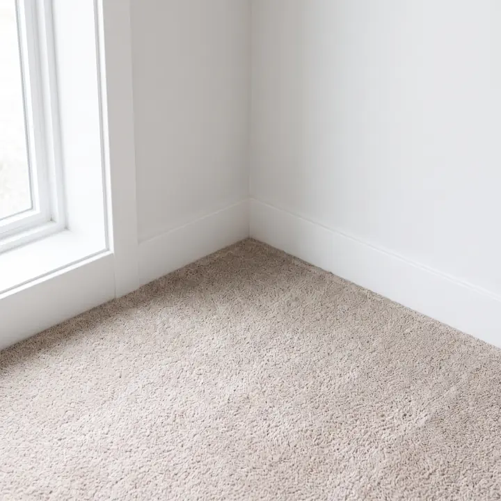 New carpet tucked tight along a white baseboard in the corner of a room