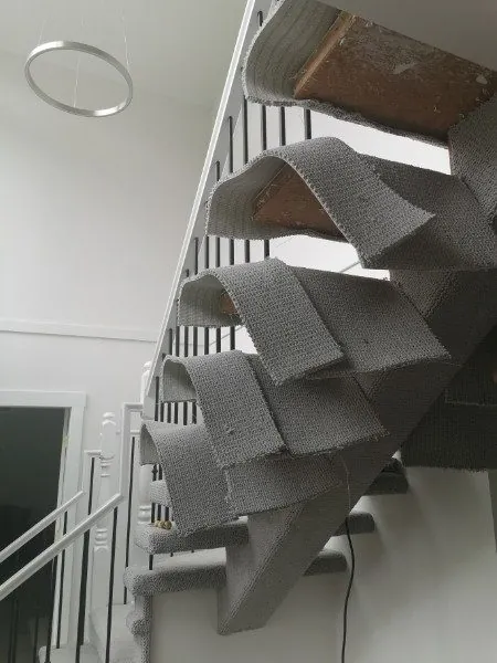 Carpet being wrapped under open stair treads in Maple Ridge